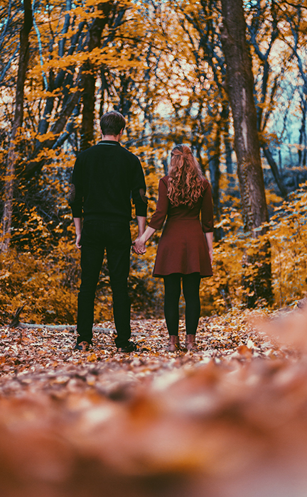 Autumn portrait of a couple holding hands in a forest