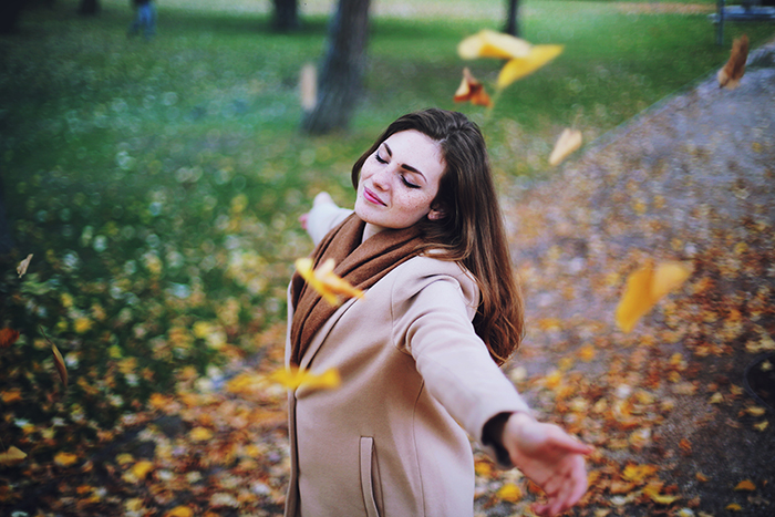 Autumn portrait of a female model throwing leaves in the air.
